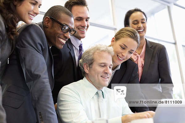 Lächelnde Geschäftsleute teilen Laptop in der Sitzung