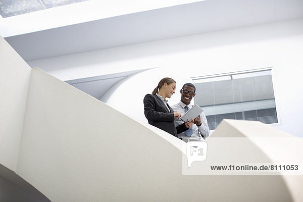 Geschäftsmann und Geschäftsfrau mit digitalem Tablett auf moderner Treppe