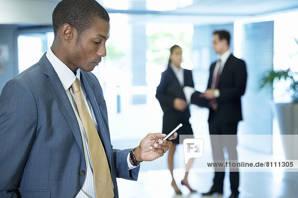 Businessman text messaging with cell phone in lobby