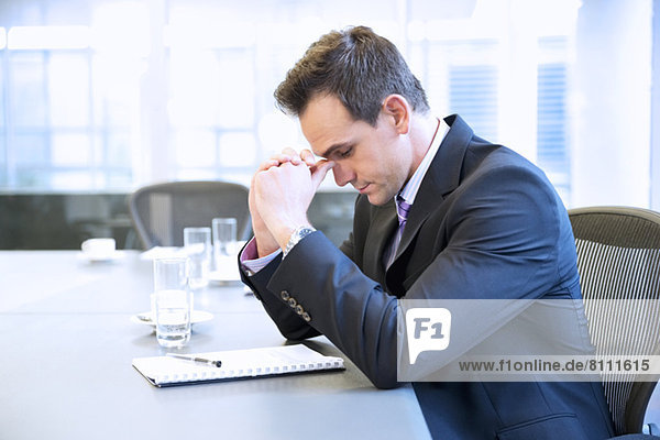 Businessman with head in hands in conference room