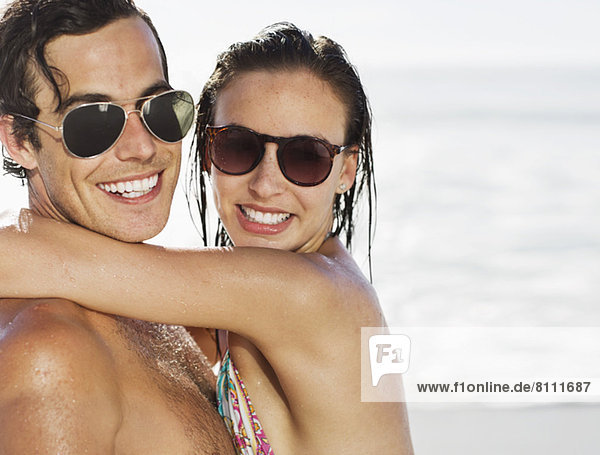 Close up portrait of smiling couple wearing sunglasses on beach
