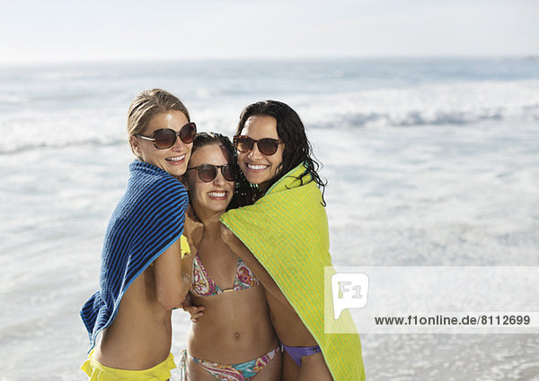 Portrait von lächelnden Freunden in Handtuch gewickelt am Strand
