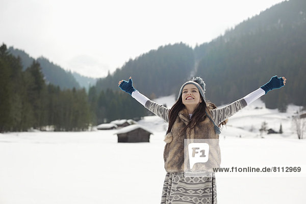 Carefree woman with arms outstretched in snowy field