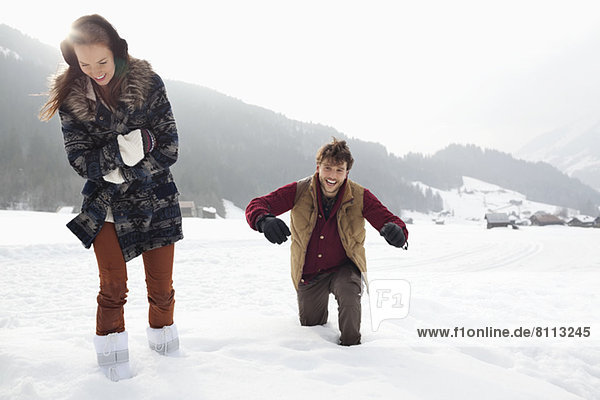 Happy couple walking through deep snow in field