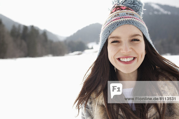 Close up portrait of happy woman wearing knit hat in snowy field