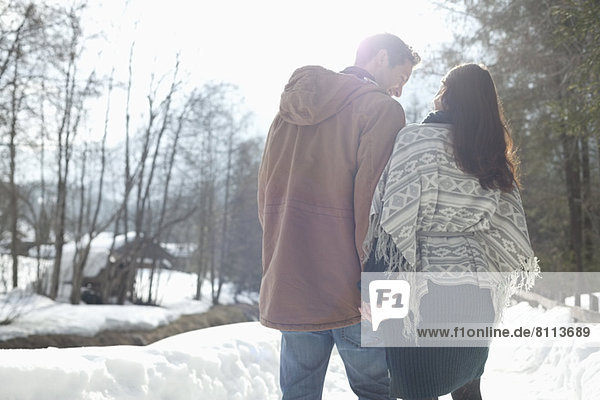 Couple holding hands and walking in snowy lane