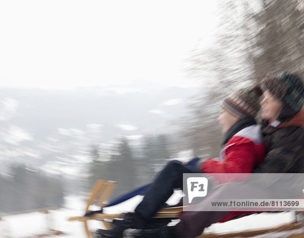 Blurred motion view of boys sledding in snow