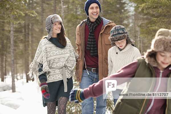 Happy family pulling Christmas tree in snow