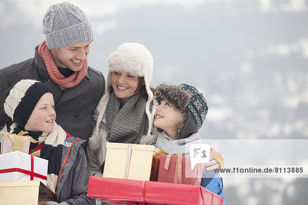 Happy family carrying Christmas gifts in snow