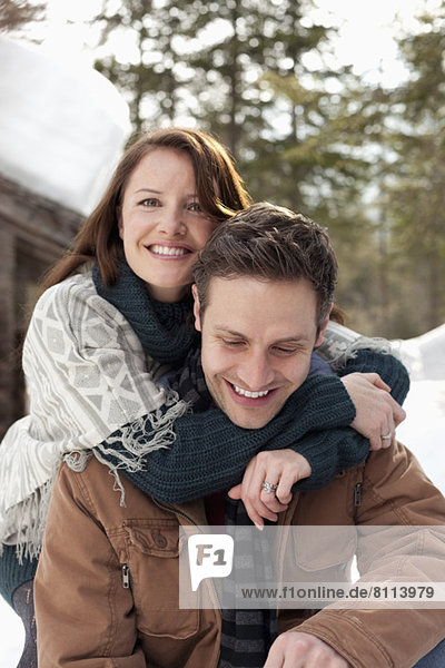 Portrait of hugging couple outside snowy cabin