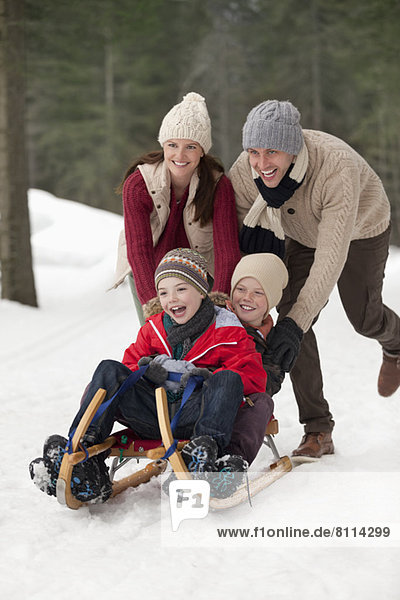 Happy family sledding in snowy woods