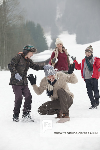 Happy family enjoying snowball fight in field