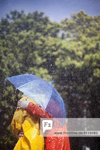 Couple hugging under umbrella in rain