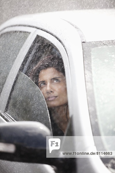 Businesswoman in car looking up at rain