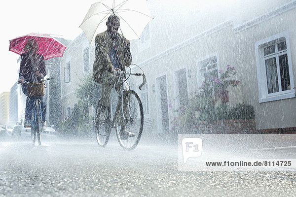 Paar mit Regenschirmen für Fahrräder bei Regen