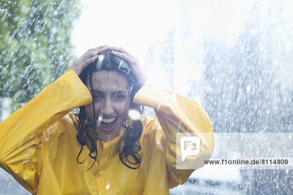 Happy woman with hands on head in rain