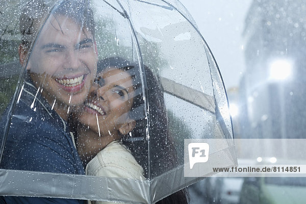 Glückliches Paar,  das sich unter dem Regenschirm umarmt.