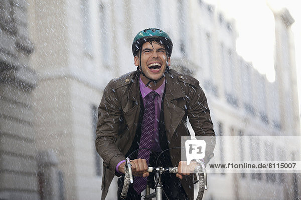 Enthusiastic businessman riding bicycle in rain