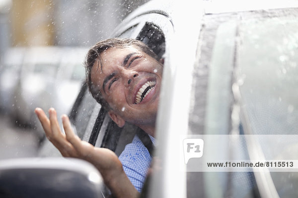 Enthusiastic man in car looking out window at rain