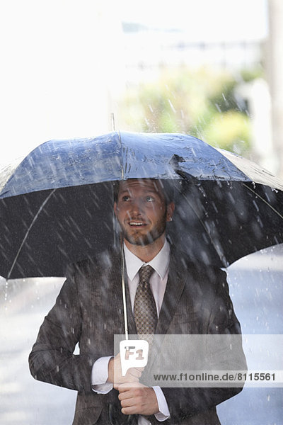 Geschäftsmann unter Schirm im Regen