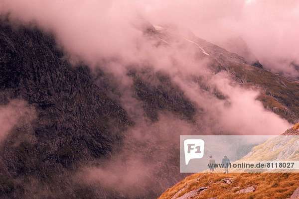 New Zealand Clouds Mountains Fog Grass Two People Trekking Hiking Misty Refreshing Slope Edge Adventure Risky Together Partner Challenge Thrill Outdoors Day Rear View Horizontal Color Image Photography