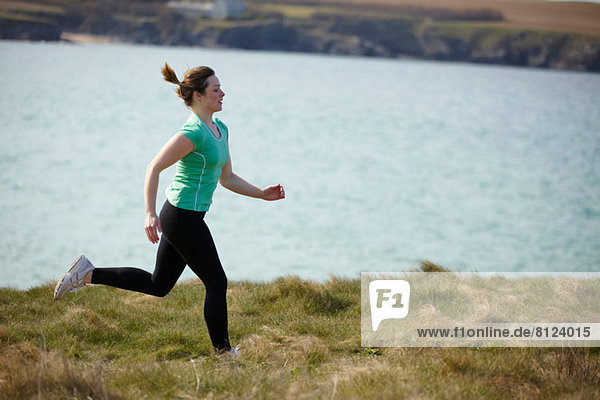 Young woman running near coast