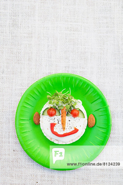 Gesicht aus frischen Lebensmitteln auf grünem Teller