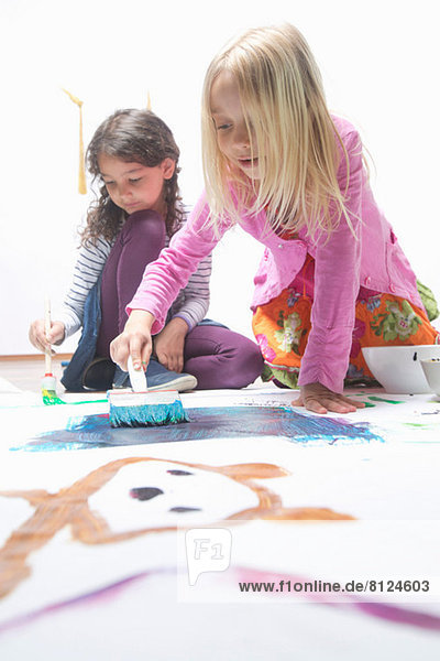 Zwei Mädchen malen auf dem Boden