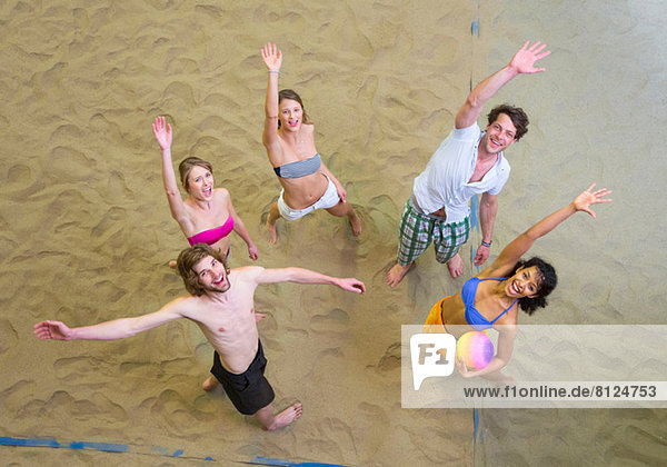 Aerial view of friends waving at indoor beach volleyball