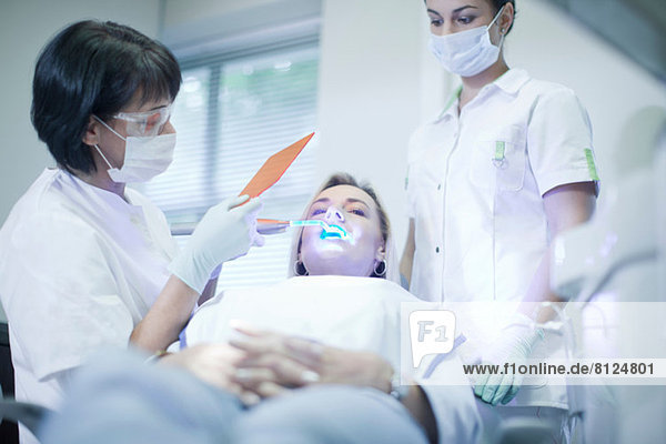 Zahnarzt  der die Zähne des Patienten mit ultraviolettem Licht bestrahlt