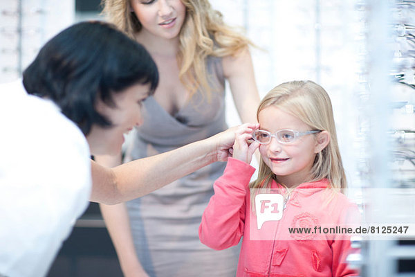 Optician guiding young girl on choice of eyeglasses