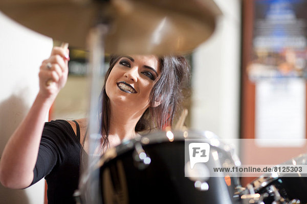 Young woman playing drum kit in music store