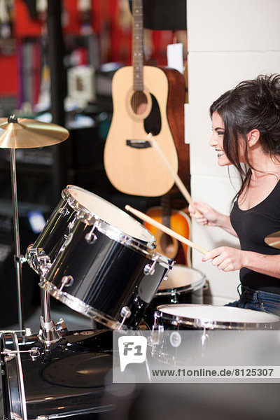 Young woman trying drum kit in music store