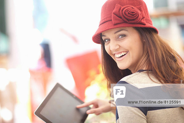 Frau mit burgunderfarbenem Hut mit digitalem Tablett