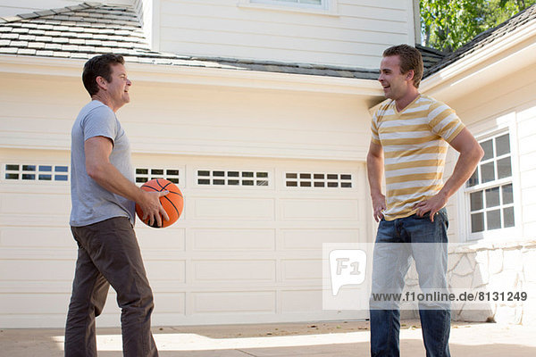 Vater hält Basketball mit erwachsenem Sohn