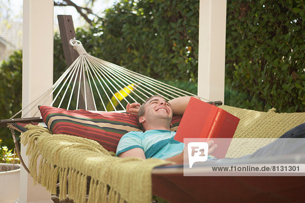Young man reading book in hammock  laughing
