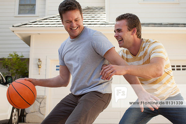 Vater und erwachsener Sohn spielen Basketball