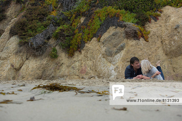 Das reife Paar liegt am Strand bei Felsen