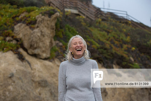 Reife Frau lacht am Strand