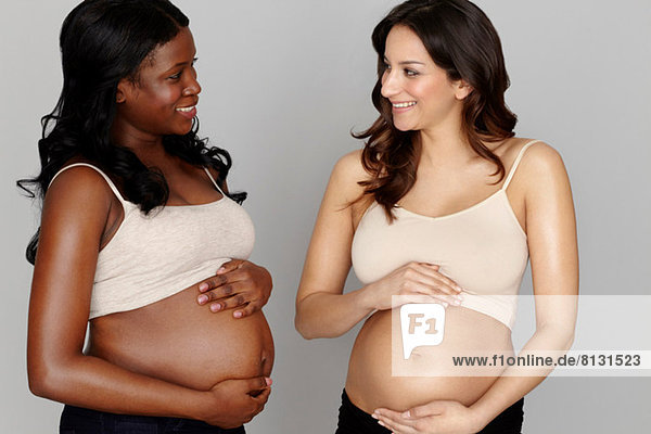 Zwei schwangere Frauen  die den Magen berühren.
