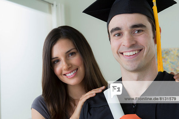 Man wearing mortarboard and graduation gown with woman