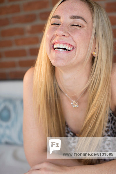 Porträt einer jungen Frau mit langen blonden Haaren  die lacht