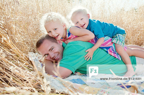 Vater mit Sohn und Tochter auf dem Feld übereinander liegend