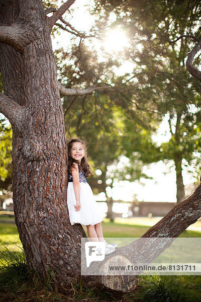 Portrait of girl standing on tree trunk