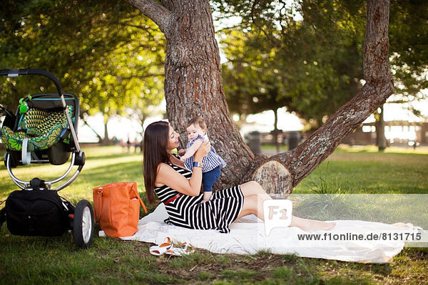 Mother sitting on picnic blanket with baby daughter