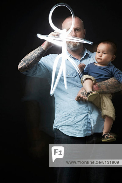 Mann zeichnet  um Baby in den Armen zu unterhalten