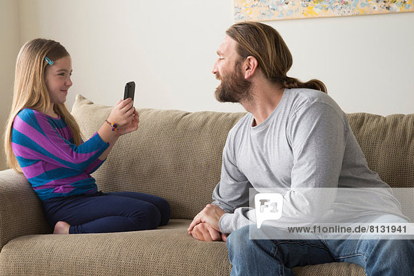 Tochter fotografiert Vater mit Smartphone