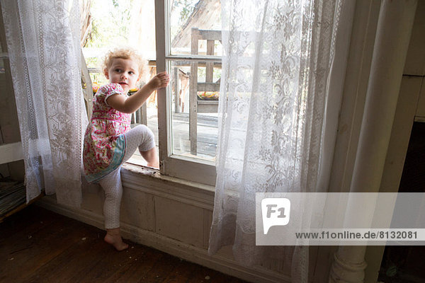 Kind klettert über geöffnetes Fenster