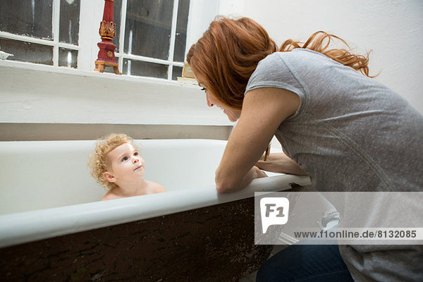 Mutter lächelt das Kind in der Badewanne an.