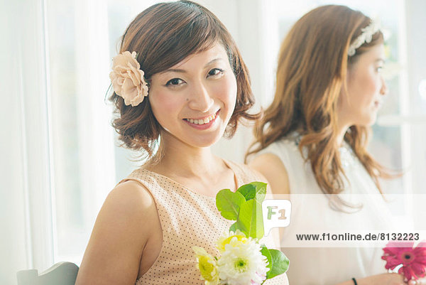 Lächelnde Frau mit Blume mit Blick auf die Kamera